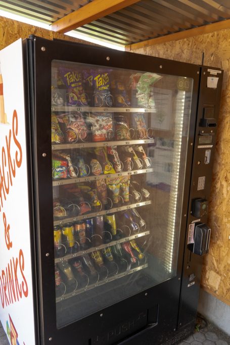 Verkaufsautomat mit Snacks und Getränken in einem überdachten Bereich.